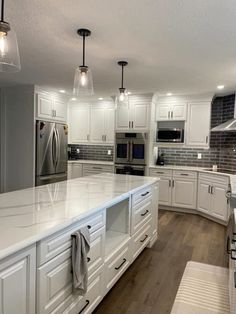 a large kitchen with white cabinets and stainless steel appliances, along with wood flooring