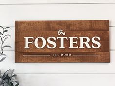 a wooden sign that says the fosterers on it next to a potted plant