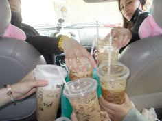 three women in the back seat of a car holding drinks