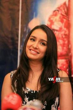 an attractive young woman sitting in front of a poster