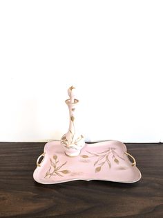 a pink and gold tray with a candle holder on it sitting on top of a wooden table