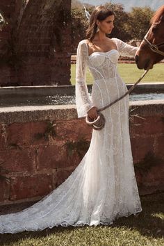 a woman in a white dress standing next to a horse