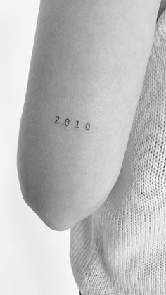 a woman with a small tattoo on her arm that reads, 2013 in black ink