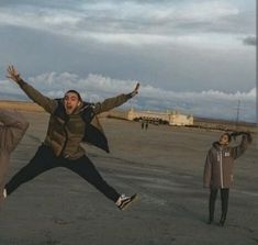 two men are jumping in the air with their arms wide open and one man is holding his hands out