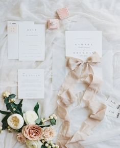 the wedding stationery is laid out on top of the bed with flowers and ribbons