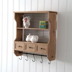 a shelf that has some cups on it and hooks attached to the wall above it