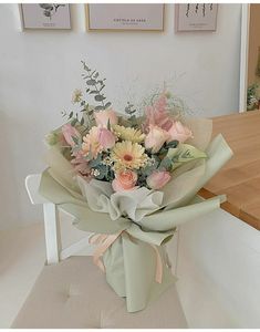 a bouquet of flowers sitting on top of a white chair next to a wooden table