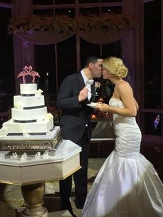 a bride and groom kissing in front of a wedding cake