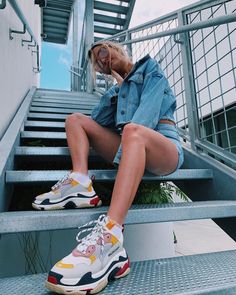 a woman sitting on some stairs wearing sneakers