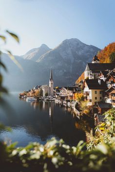 a small town on the edge of a lake with mountains in the background and trees around it