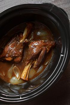 a slow cooker filled with meat and onions