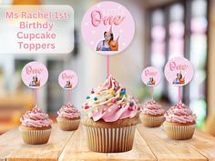 cupcakes with pink frosting and decorations are on a wooden table in front of a sign that says,'my rachellist birthday cupcake toppers '