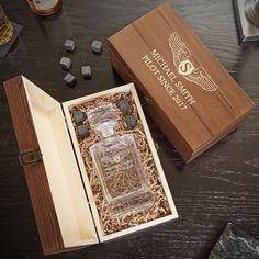 an open wooden box with some liquor in it on a table next to other bottles