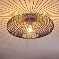 a light that is hanging from the ceiling in front of a lamp shade with lines on it