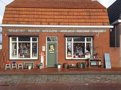 an old brick building with several windows and chairs outside it on the side of the street