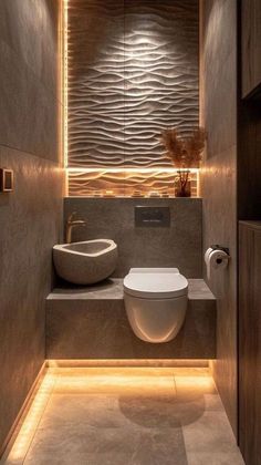 a toilet and sink in a bathroom with lights on the wall above it's counter