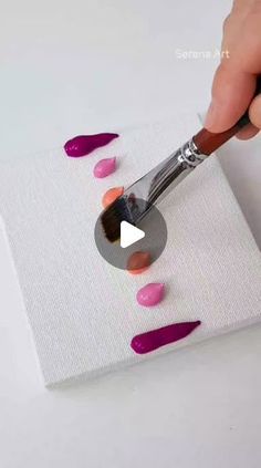 someone using a paint brush to decorate a piece of paper with pink and purple nail polish