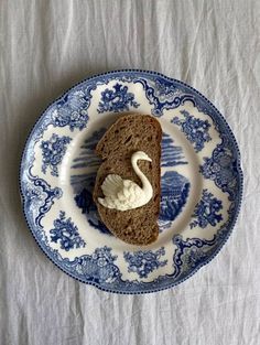 a piece of bread with cream on it sitting on a blue and white china plate