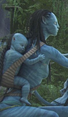 an alien is holding a baby in his arms while standing next to another creature on the ground