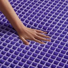 a person's hand on top of a purple plastic mat with holes in it