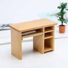 a small wooden desk with shelves and a potted plant next to it on a white surface