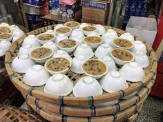 several bowls filled with different types of food on display in a store setting, including soups and teapots