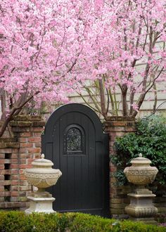 a black door surrounded by pink flowers and trees