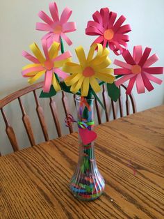 a vase filled with paper flowers on top of a wooden table