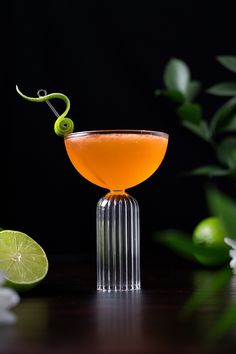 an orange cocktail garnished with a green snake