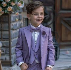 a young boy wearing a purple suit and bow tie