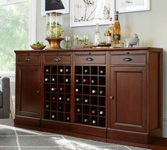 a wine cabinet with many bottles and glasses on it in a living room next to a couch