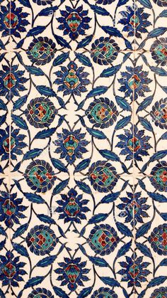 an intricately designed tile with blue flowers and leaves on it's sides,