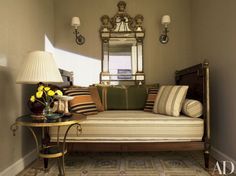 a living room with a couch, mirror and lamp on the side table in front of it