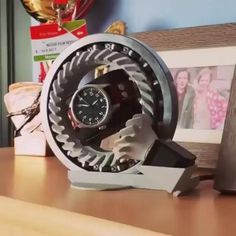 a clock that is sitting on top of a wooden table next to pictures and other items