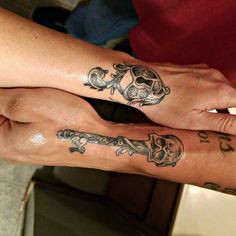 two people with matching tattoos on their arms holding each other's hands and looking at the camera