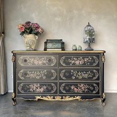 an ornate black dresser with flowers on it