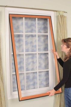 a woman standing next to a window with an open pane on it's side