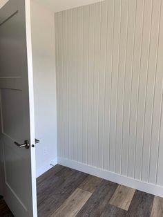 an empty room with wood flooring and white paneling on the walls is seen in this image