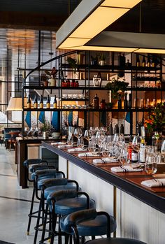 a long bar with lots of bottles and glasses on top of it next to chairs