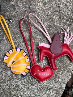 three pieces of leather are laid out on the ground, one has a heart shaped brooch