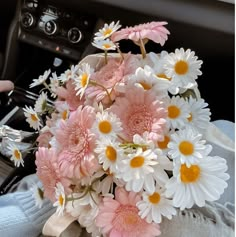 a bouquet of pink and white daisies in a car