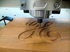 a close up of a machine cutting wood with scissors on the table next to it