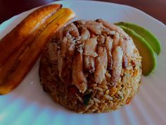 a white plate topped with rice covered in meat and veggies next to a pickle