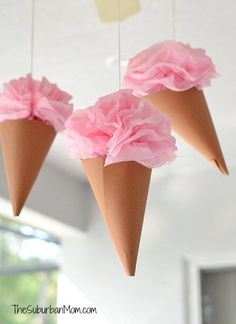 three paper cones with pink flowers hanging from strings in a kitchen or dining room area