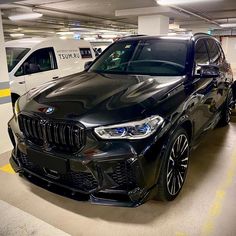 two cars parked in a parking garage next to each other on the floor and one is black