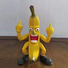 a toy banana that is sitting on the floor with its hands up and mouth wide open