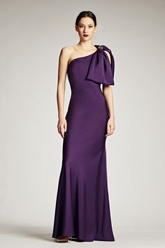 a woman in a long purple dress with an open shoulder and bow at the back