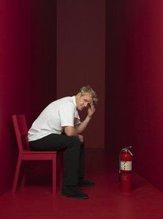 a man sitting on a red chair next to a fire extinguisher