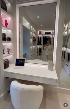 a white vanity with a mirror and stool in front of it, all lit up