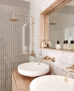 two white sinks sitting under a bathroom mirror next to a wooden counter with soap dispensers on it